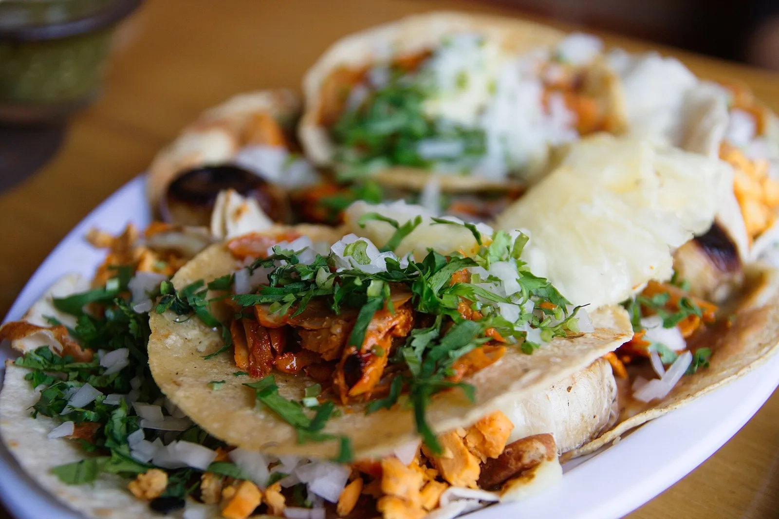 A plate of tacos al pastor topped with onion and cilantro. The photo was not taken at a Wilmington restaurant.