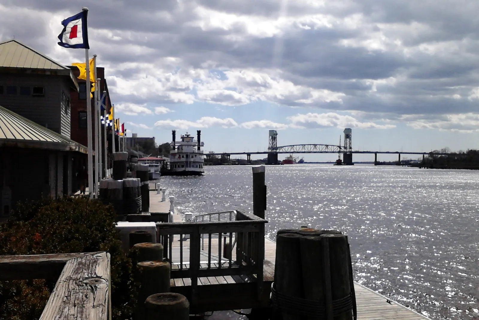 The Cape Fear River and the Riverwalk in downtown Wilmington, with the Cape Fear Memorial Bridge in the distance.